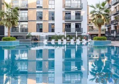 a swimming pool in front of a building with palm trees at Unique 1BR in Belgravia Square, JVC - Host & Stay in Dubai