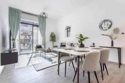 a dining room and living room with a table and chairs at Unique 1BR in Belgravia Square, JVC - Host & Stay in Dubai