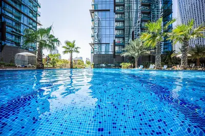 a large swimming pool with palm trees and buildings at Luxurious apartment in Dubai Marina in Dubai