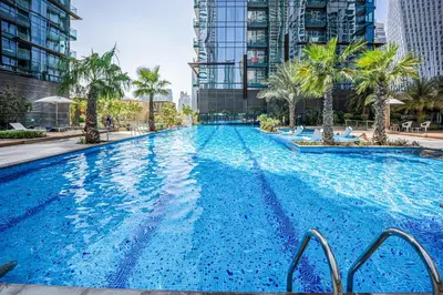 a large swimming pool with palm trees and buildings at Luxurious apartment in Dubai Marina in Dubai