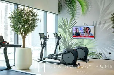 a gym with two exercise bikes and a tv on the wall at LUX The Vida Marina Residence 3 in Dubai