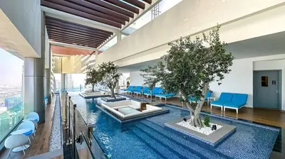 a lobby with a pool with trees and blue chairs at High Floor 2 Bedroom Gem - Burj Khalifa Views in Dubai
