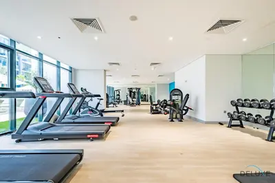 a gym with rows of treadmills and machines at Beautiful Studio at Azizi Riviera 17, Al Merkadh by Deluxe Holiday Homes in Dubai