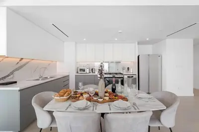 a white kitchen with a table with chairs and a tableasteryasteryasteryasteryastery at 3Bed Private Beach - Belle vie à La Vie Dubai in Dubai