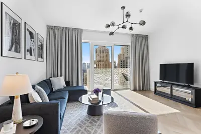 a living room with a blue couch and a tv at Elegant and Modern 1BR Apt in JBR with Beach Access in Dubai