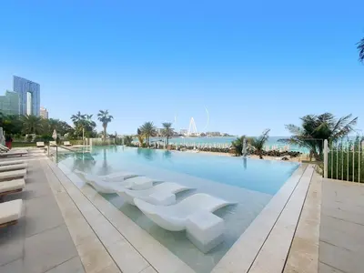 a large swimming pool with white seats in the water at Elegant and Modern 1BR Apt in JBR with Beach Access in Dubai