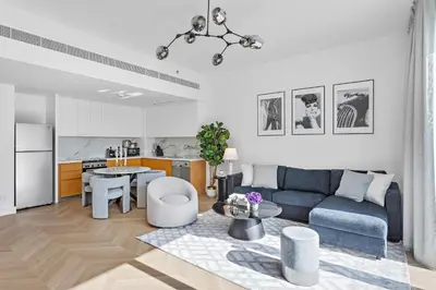 a living room with a blue couch and a kitchen at Elegant and Modern 1BR Apt in JBR with Beach Access in Dubai
