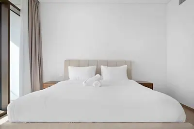 a large white bed with white sheets and pillows at Amazing 2br with a lagoon view in Creek Harbour in Dubai