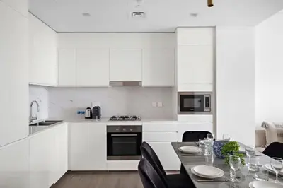 a kitchen with white cabinets and a table with chairs at Amazing 2br with a lagoon view in Creek Harbour in Dubai