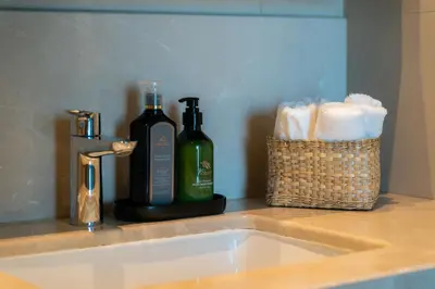 a sink with two bottles of wine and a basket of towels at Elite Escape Holiday Home - 1 BHK Getaway with Dubai Mall Access - 1502 in Dubai