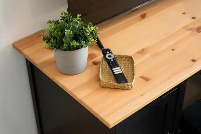 a remote control sitting on a wooden table with a plant at Elite Escape Holiday Home - 3 BHK Getaway with Burj Khalifa View and Dubai Mall Access - 1505 in Dubai