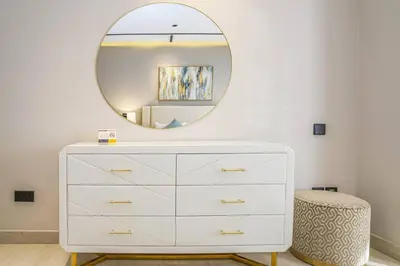 a white dresser with a round mirror above it at New Arabian Shams 2 JBR Sea View in Dubai