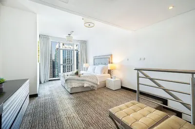 a white bedroom with a bed and a balcony at Whispers of the Wind by Lagom Vacation Homes in Dubai
