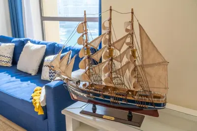 a model boat on a table next to a blue couch at 7 Beds / JBR / Sea, JBR Beach and Ain Dubai Views / 3 min walk from JBR Beach / Large Groups and Families / Ideal Vacation Location in Dubai