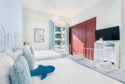 a room with four beds and a flat screen tv at 7 Beds / JBR / Sea, JBR Beach and Ain Dubai Views / 3 min walk from JBR Beach / Large Groups and Families / Ideal Vacation Location in Dubai