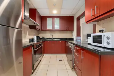 a kitchen with red cabinets and a stainless steel refrigerator at 7 Beds / JBR / Sea, JBR Beach and Ain Dubai Views / 3 min walk from JBR Beach / Large Groups and Families / Ideal Vacation Location in Dubai