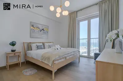 a white bedroom with a bed and a large window at Mira Holiday Homes - Newly 1 bedroom with sea view in Dubai