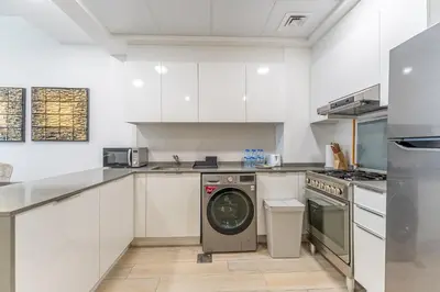 a kitchen with white cabinets and a washing machine at HAVN - 2 Bedroom Apartment in Bloom Tower, JVC in Dubai