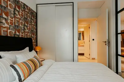 a bedroom with a white bed with a large mirror at Coolest 1 BR in Dubai Hills close to the Park in Dubai