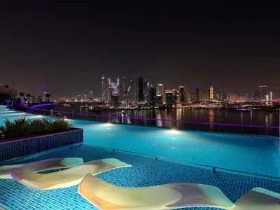 a swimming pool with a city skyline at night at Beachside Bliss: Stylish New Studio at Seven Palm in Dubai