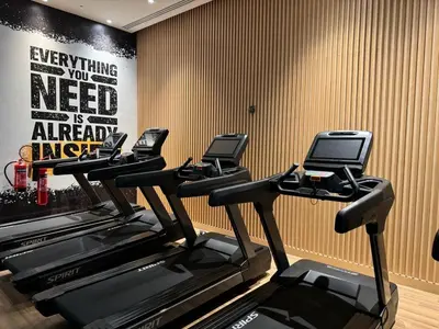 a gym with five treadmills in a room at Beachside Bliss: Stylish New Studio at Seven Palm in Dubai