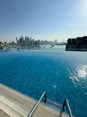 a large swimming pool with a city in the background at Beachside Bliss: Stylish New Studio at Seven Palm in Dubai