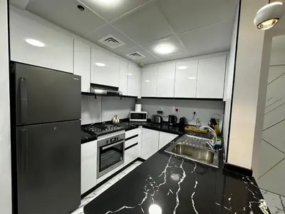 a kitchen with white cabinets and a black refrigerator at Stay in heart of Dubai Marina, walk to JBR! #3 in Dubai