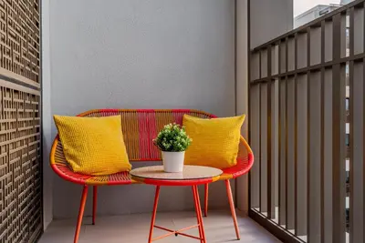 a red chair with yellow pillows on a balcony at Coastal Vibe I 1BDR apartment in Creek Beach I Summer 2 in Dubai