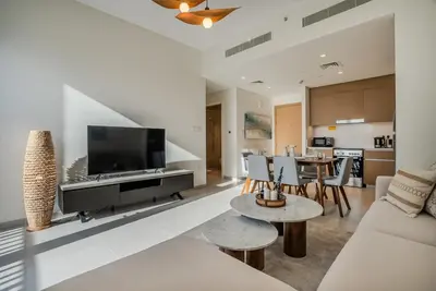 a living room with a tv and a couch and tables at Coastal Vibe I 1BDR apartment in Creek Beach I Summer 2 in Dubai