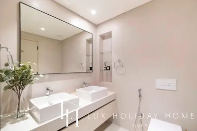 a bathroom with two sinks and a mirror at LUX The Marina Vista Beachfront Suite in Dubai