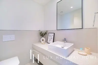 a white bathroom with a sink and a mirror at LUX The Marina Vista Beachfront Suite in Dubai