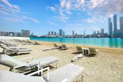 a beach with chaise lounges and chairs on the sand at LUX The Marina Vista Beachfront Suite in Dubai