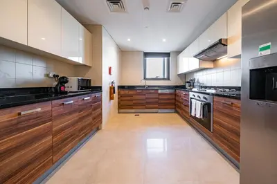 a large kitchen with wooden cabinets and stainless steel appliances at SettlerHomes - Sparkle Tower 2 With Marina & Sea View in Dubai