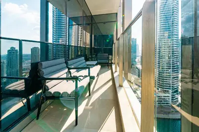 a woman sitting on the balcony of a building at SettlerHomes - Sparkle Tower 2 With Marina & Sea View in Dubai