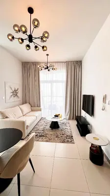 a white living room with a couch and a tv at Stylish & Roomy 1BR in the Heart of the City in Dubai