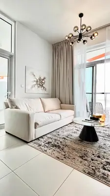 a white living room with a couch and a table at Stylish & Roomy 1BR in the Heart of the City in Dubai