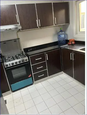 a kitchen with wooden cabinets and a stove top oven at Studio Flat in AWS only Bachelor no family no children in Dubai