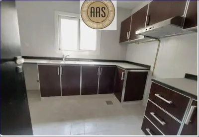 a kitchen with brown cabinets and a plate on the wall at Studio Flat in AWS only Bachelor no family no children in Dubai