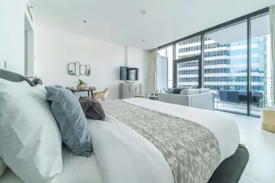 a white bedroom with a large bed and a living room at Frank Porter - Marquise Square Tower in Dubai