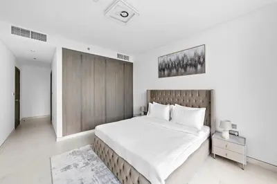 a bedroom with a large bed with white sheets at ALiving Classy 2BR I Lagoons View I District One Residence 7 in Dubai
