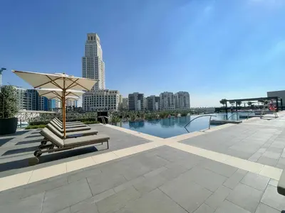a patio with a bench and an umbrella and water at Luxe 1-Bedroom Elegance in Palace Residences in Dubai