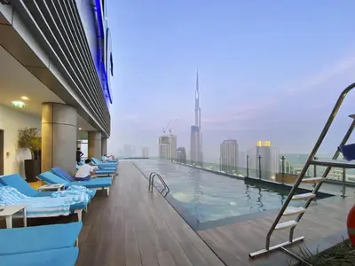 a pool on the top of a building with chairs at White Sage - Deluxe Apartment With Unobstructed Sea Views in Dubai