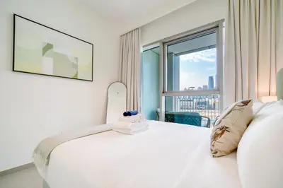 a bedroom with a white bed and a large window at Downtown - 2BR Apartment with Burj Khalifa View in Dubai