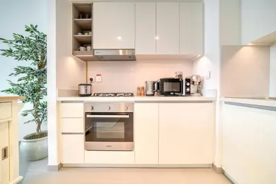 a kitchen with white cabinets and a stove at Downtown - 2BR Apartment with Burj Khalifa View in Dubai
