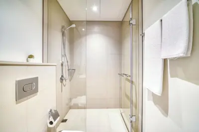 a white bathroom with a shower and a toilet at Downtown - 2BR Apartment with Burj Khalifa View in Dubai