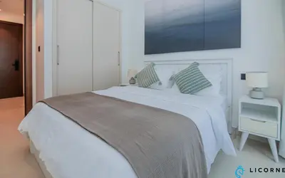 a white bedroom with a large bed with a blanket at Inviting 2BR Apartment - Only 10 Mins to Downtown - Sobha Creek Vista Reserve in Dubai