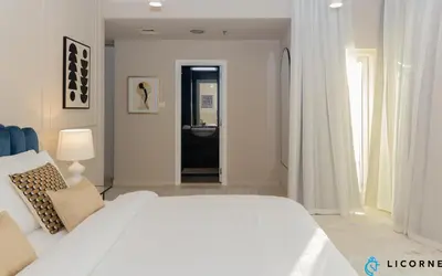 a white bedroom with a white bed and a bathroom at Prime Spacious 2 BR Apt, Burj Khalifa & Canal View - Scala Tower in Dubai