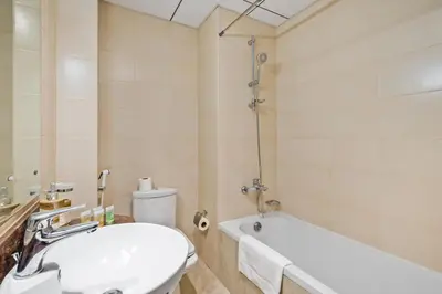 a bathroom with a sink and a tub and a toilet at Modern Sports City Studio Pool, Gym & Stadium in Dubai
