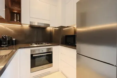 a kitchen with white cabinets and a stainless steel refrigerator at 1BR Gem with Stunning Marina Views, Close to Metro in Dubai