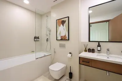 a white bathroom with a toilet and a sink at 1BR Gem with Stunning Marina Views, Close to Metro in Dubai